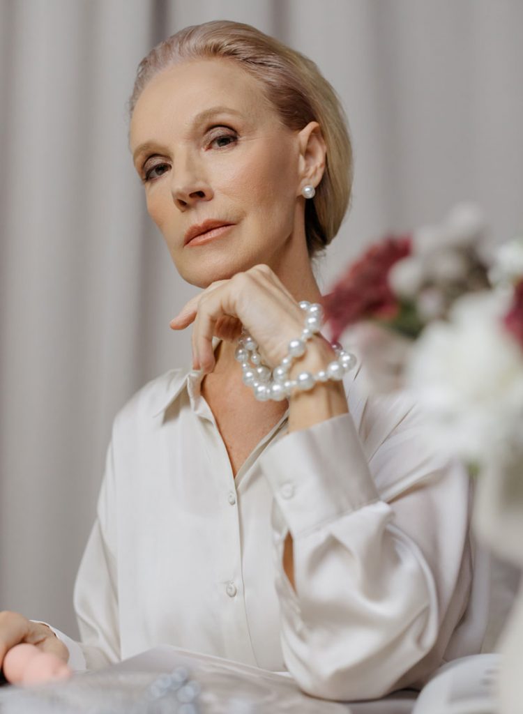 Woman in White long Sleeves Holding a Pearl Necklace